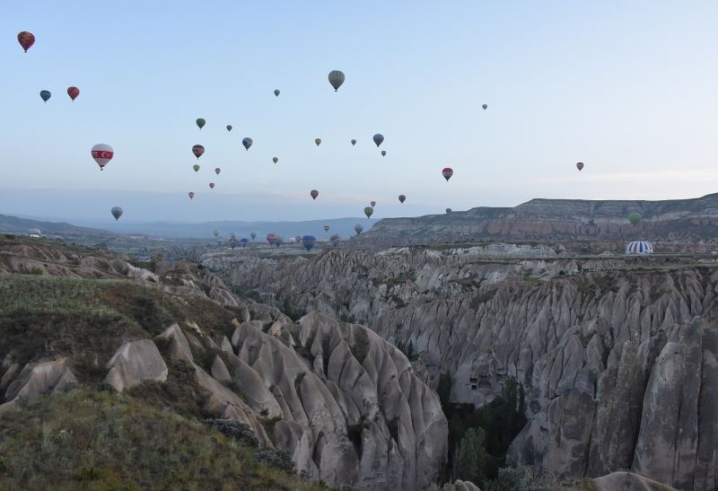 Dutzende Heißluftballone über den erodierten Tufftälern bei Göreme im Morgengrauen