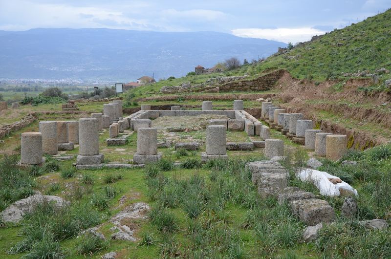 Säulenstümpfe des dorischen Tempels des Zeus Chrysaoreus in Alabanda an einem grünen Hang, dahinter die Ebene