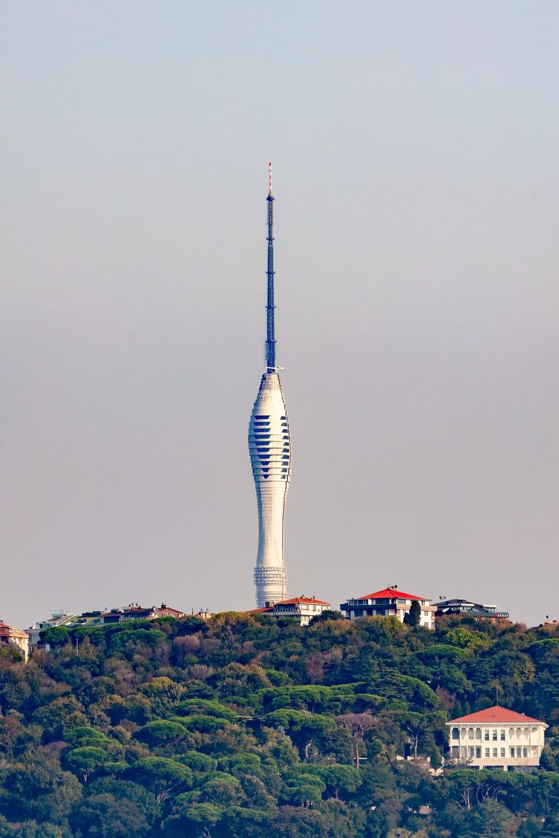 The white, tapering Çamlıca Tower and its mast rising above the wooded hill of Çamlıca