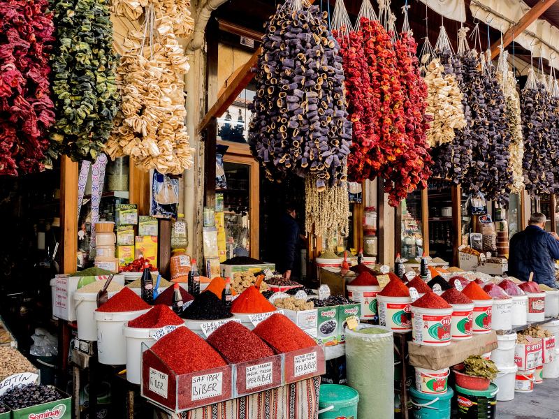 Dried peppers and aubergines hanging above heaps of spices at a shop in a Gaziantep bazaar