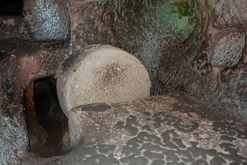 A round millstone door beside a passage in Özkonak Underground City