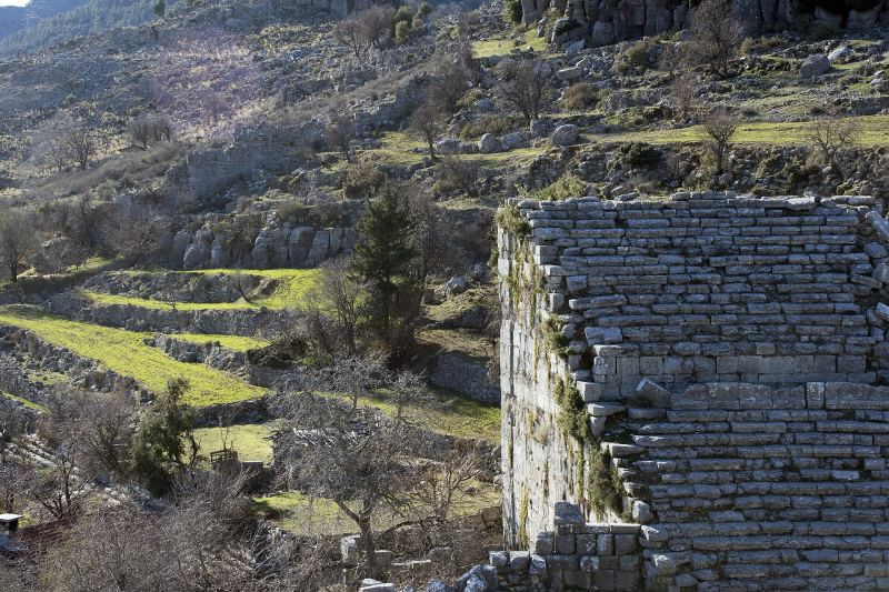 Die steinernen Sitzreihen des Theaters von Selge, dahinter Terrassenfelder und felsige Hänge